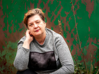 A thoughtful Mature plump woman walks the streets of the old city. On the background of the old green gate.