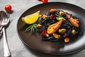 Black spaghetti. Seafood pasta with mussels and prawns over concrete background. Mediterranean food.