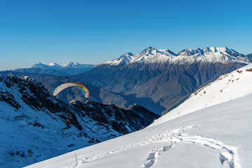 Snow covered mountain with flighting skydiver
