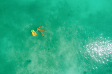 Fototapeta na wymiar Aerial view of slim woman swimming on the transparent turquoise sea. Summer seascape with girl, beautiful waves, colorful water. Top view from drone