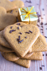 Top view of stack of heart shaped ginger cookies with chocolate noodles and golden Christmas package in vertical
