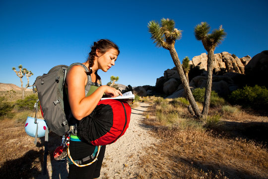A woman refers to a climbing guide book near Turtle Rock in the Hidden Valley Picnic Area at Joshua Tree National Park.