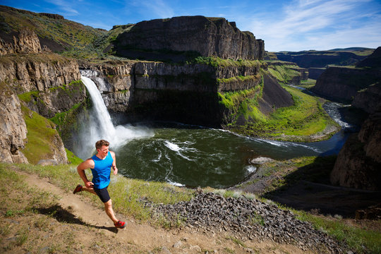 Fitness trainer goes for an exposed trail run around the rim of the Palouse Falls in southeastern Washington State. The short-but-scenic trail drops down from the main parking area and runs along the Palouse River, falls and surrounding ampitheater.