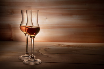 Two tasting glasses of whiskey on a wooden background