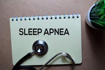 Sleep Apnea write on a book with stethoscope. Isolated on wooden table