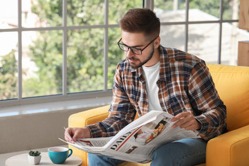 Handsome man reading newspaper at home