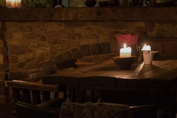 Big candle in a plate on a wooden table. Interior lighting with candles. Romantic interior in the dark.