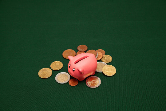 Piggy bank in the form of a pink pig and euro coins and cents on a green background