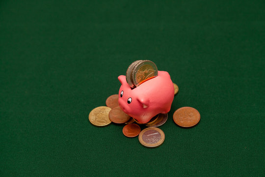 Piggy bank in the form of a pink pig and euro coins and cents on a green background