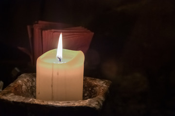 Big candle in a plate on a wooden table. Interior lighting with candles. Romantic interior in the dark.