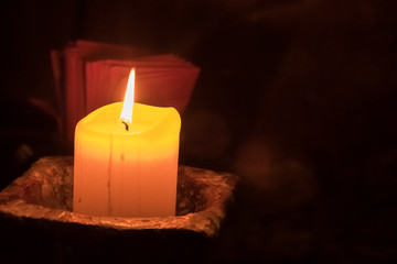Big candle in a plate on a wooden table. Interior lighting with candles. Romantic interior in the dark.