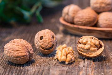 Walnuts in wooden bowl. Whole walnut on wood table with green leaves