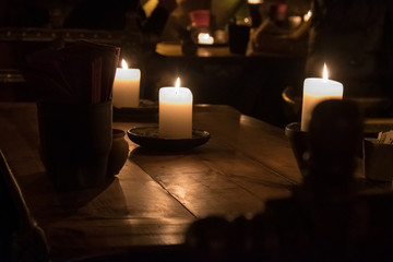 Big candle in a plate on a wooden table. Interior lighting with candles. Romantic interior in the dark.