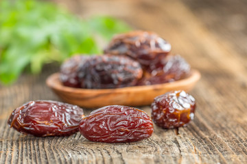 Juicy dates in a bowl on a old wooden table .