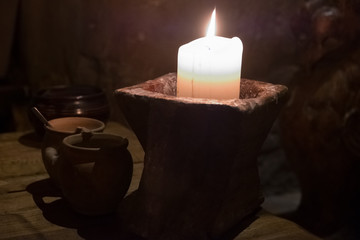 Big candle in a plate on a wooden table. Interior lighting with candles. Romantic interior in the dark.