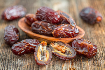 Juicy dates in a bowl on a old wooden table .