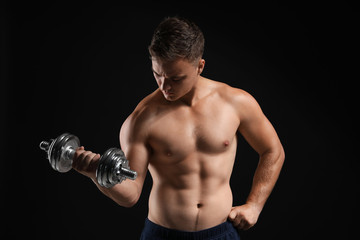 Fototapeta na wymiar Handsome male bodybuilder with dumbbell on dark background