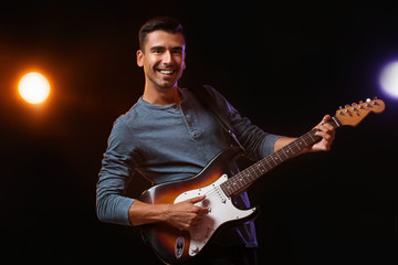 Handsome man playing guitar on stage