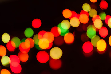bright defocused multicolored new years lights on dark blurred background with copy space