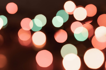 selective focus of defocused bright shiny multicolored christmas lights with backdrops for wallpaper on dark background