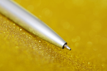 Silver fountain pen lies on a bright golden surface. Signing a contract or permit. Time for study...