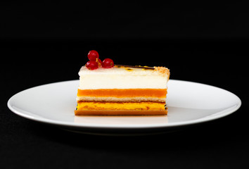 multi layered beautiful cake with white cream and red currants, on a white plate, dessert serving