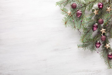 Fir branch with Christmas decoration on white shabby wooden board with copy space for text. Flat...