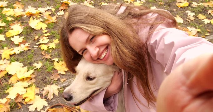 Young woman taking selfie with cute dog in autumn park