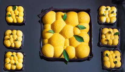 Orange or tangerine shape mousse pastry dessert covered with orange velour (velvet spray) on dark mirror background. Modern European cake. French cuisine.