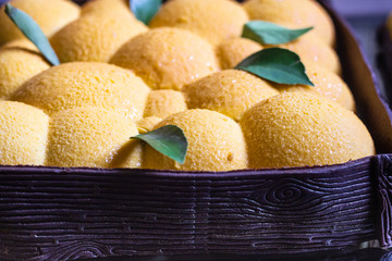 Orange or tangerine shape mousse pastry dessert covered with orange velour (velvet spray) on dark mirror background. Modern European cake. French cuisine.