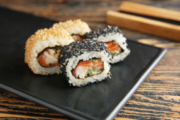 Plate with tasty sushi rolls on table, closeup