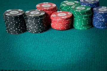 Poker chips of various colors and amounts on green carpet. Hotizontal image