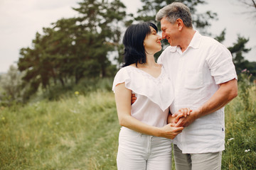 Obraz premium Adult couple in a summer field. Handsome senior in a white shirt. Woman in a white blouse