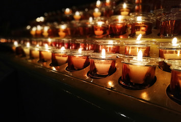 Candles in a church, cathedral or temple, in yellow transparent candlesticks. The concept of mourning. We remember, we grieve. Selective focus, side view, copy space