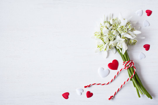 Bouquet of snowdrops and red white hearts on a wooden background for congratulations, holiday Martisor
