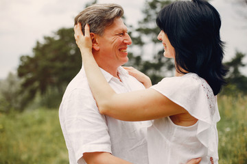 Obraz premium Adult couple in a summer field. Handsome senior in a white shirt. Woman in a white blouse