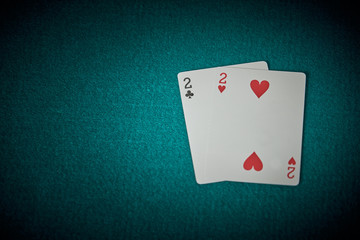 Two cards of trebles and two of hearts on a green carpet of poker game. Superios view.