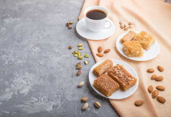 traditional arabic sweets and a cup of coffee on a gray concrete background. side view, copy space.