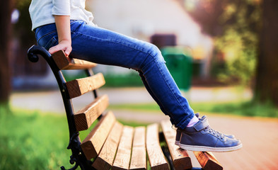 Girl sitting on the top of a park bench, close up photo