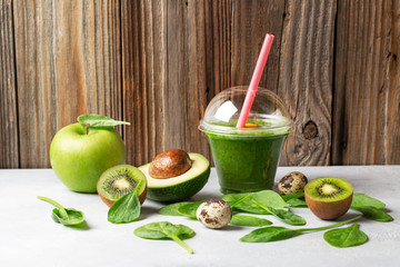 Green healthy smoothie of spinach, avocado and quail egg on white background and wood wall
