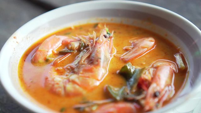 Spicy Soup with Prawn in a bowl. Tom Yum Goong. Slide shot. Thai food