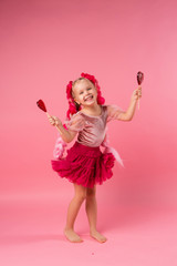 little girl with braids of pink kanekalon holds a heart-shaped Lollipop on a pink background. refusal of sweets. the concept of Valentine's day