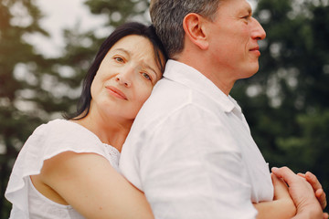 Adult couple in a summer field. Handsome senior in a white shirt. Woman in a white blouse