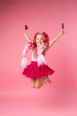 little girl with braids of pink kanekalon holds a heart-shaped Lollipop on a pink background. refusal of sweets. the concept of Valentine's day