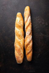 Fresh hot two baguettes on dark background. Top view.