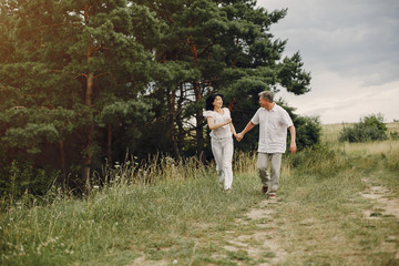 Adult couple in a summer field. Handsome senior in a white shirt. Woman in a white blouse