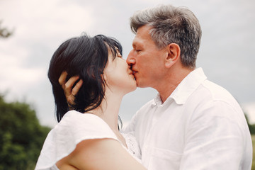 Fototapeta premium Adult couple in a summer field. Handsome senior in a white shirt. Woman in a white blouse