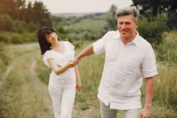 Fototapeta na wymiar Adult couple in a summer field. Handsome senior in a white shirt. Woman in a white blouse