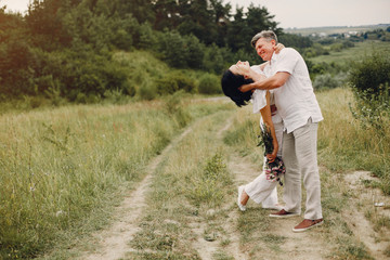 Adult couple in a summer field. Handsome senior in a white shirt. Woman in a white blouse