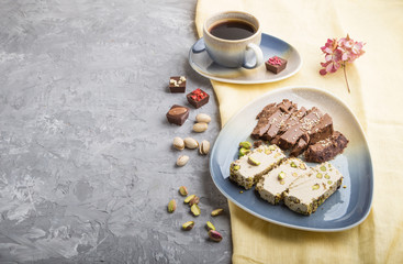 traditional arabic sweets sesame halva with chocolate and pistachio and a cup of coffee on a gray concrete background. side view, copy space.